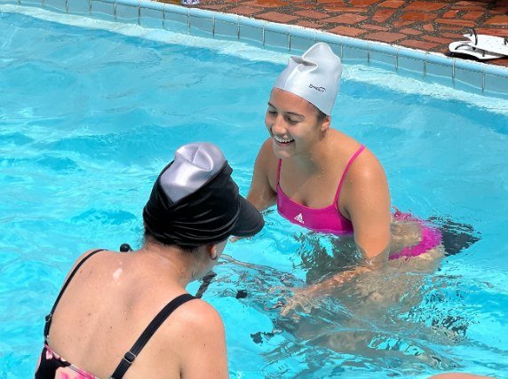 Dos alumnas sonriendo en la piscina durante una clase